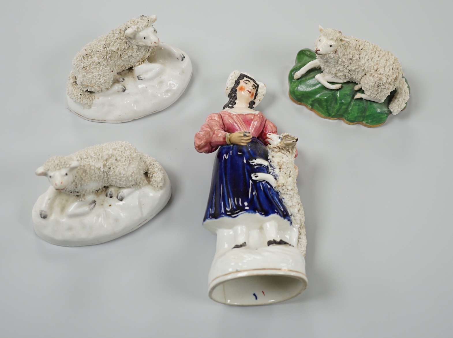 Three small Staffordshire models of recumbent sheep on oval mounted bases, together with a Staffordshire model group of a shepherdess, c.1830-50, (4). Tallest 17.5cm, Provence: Dennis G.Rice collection